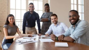 Portrait of happy diverse young businesspeople gather at boardroom table