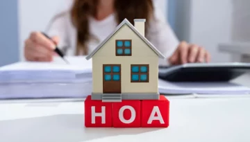 Close-up Of House Model Over HOA Blocks In Front Of Businesswoman (R) (S)