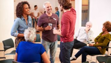 Group Of People Socializing After Meeting In Community Center