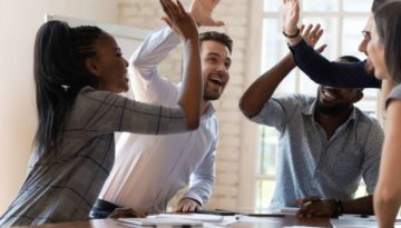 Multiracial euphoric business team people give high five at office table