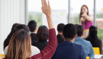 young businesswoman raising hand to question from Speaker in Seminar. Group Meeting . Conference Concept . Rear back view