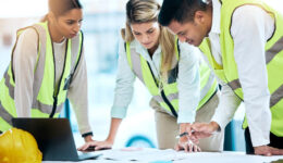 Architect, team and meeting in blueprint planning for construction, architecture or project collaboration. Group of contractors discussing floor plan or teamwork strategy for industrial architecture