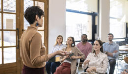 Woman Lecturer Giving Presentation to Businesspeople