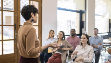 Woman Lecturer Giving Presentation to Businesspeople